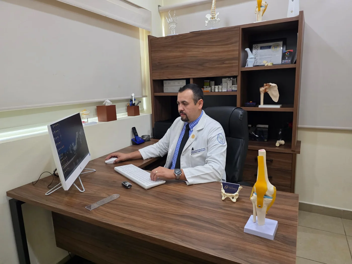 El Dr. Alan Polanco trabaja en la computadora de su consultorio.