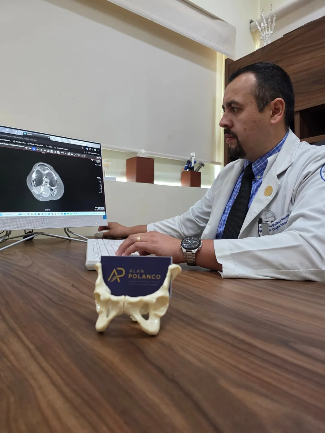 El Dr. Alan Polanco revisa un estudio de imagen de rodilla en el monitor de su consultorio.